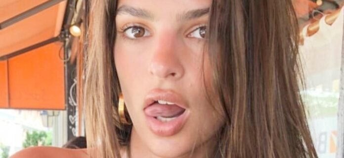 Emily Ratajkowski 'Can't Keep Her Clothes On' While Sunbathing In Only A Baseball Cap